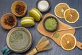 Measuring spoon and green matcha powder on wooden board. Dry orange slices and spices in bowls. Macaron biscuits and matcha tea in Royalty Free Stock Photo