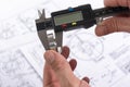 Measuring a steel part with a vernier caliper in a personÃ¢â¬â¢s hand. Quality control. Engineer when measuring the diameter of a Royalty Free Stock Photo