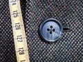 Measuring tape and buttoned button on tweed jacket Royalty Free Stock Photo