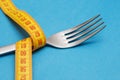 Measuring tape with fork on blue background. Concept of weight loss. Weight management. Healthy lifestyle. Weight loss health Royalty Free Stock Photo