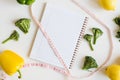 Measuring tape, note pad with clean pages and fresh vegetables and fruits on white background Royalty Free Stock Photo