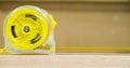 Measuring tape placed on the wooden table in a domestic joinery with a neutral background and copy space Royalty Free Stock Photo