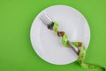 measuring tape, plate and cutlery on a green background Royalty Free Stock Photo