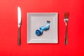 Measuring tape in a plate with fork and knife on both sides on red background. Top view of weight loss concept Royalty Free Stock Photo