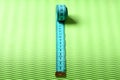Measuring tape roll in cyan color on green texture background Royalty Free Stock Photo