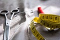 Measuring tape, scissors and reel of red thread on gray fabric Royalty Free Stock Photo
