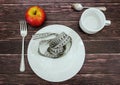 Diet concept. Measuring tape in a white plate on a wooden table and an apple. Royalty Free Stock Photo