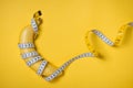 Measuring tape wrapped around a banana isolated on a yellow back Royalty Free Stock Photo