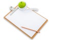 Measuring tape wrapped around a green apple and clipboard Royalty Free Stock Photo