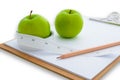 Measuring tape wrapped around a green apple and clipboard Royalty Free Stock Photo