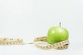 Measuring tape wrapped around a green apple.