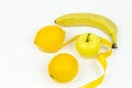 A measuring tape wrapped around a green apple and two lemons and a banana as a symbol of diet. Royalty Free Stock Photo