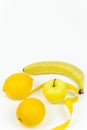 A measuring tape wrapped around a green apple and two lemons and a banana as a symbol of diet Royalty Free Stock Photo