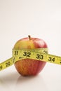 Weight loss solution concept. Red apple with measure tape. Royalty Free Stock Photo