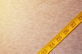 The measuring tape of yellow color with numerical indicators in the form of centimeters or inches lies on a gray knitted fabric. Royalty Free Stock Photo