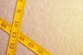 The measuring tape of yellow color with numerical indicators in the form of centimeters or inches lies on a gray knitted fabric. Royalty Free Stock Photo