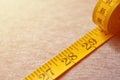 The measuring tape of yellow color with numerical indicators in the form of centimeters or inches lies on a gray knitted fabric. Royalty Free Stock Photo