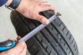 Measuring the tire tread with a tape measure. Worn tire technical check. Close-up