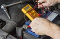 Measuring voltage on car battery. Change weak battery. Royalty Free Stock Photo