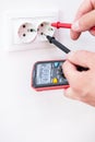Measuring the voltage in the socket with a professional digital multimeter. Profession electrician, the process of installing Royalty Free Stock Photo