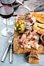 Meat appetizer selection. Salami, prosciutto, bread sticks, baguette, olives and sun-dried tomatoes, two glasses of red