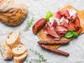 Meat appetizers selection, a loaf of rustic village bread and ba Royalty Free Stock Photo