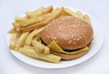 Meat burger with French fries on a white plate. Delicious fast food breakfast. Hamburger Royalty Free Stock Photo