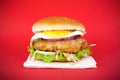 Meat burger  on a red background.Large homemade burger with fresh lettuce salad, egg and melted cream cheese on a cutlet Royalty Free Stock Photo