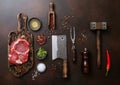 Meat cleavers,tenderizer,fork,knife and other kitchen meat utensils with oil,herbs,salt and pepper on dark background with raw rib Royalty Free Stock Photo