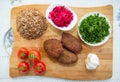 Meat cutlets, baked buckwheat on a wooden board . Red cabbage sauerkraut . Garlic, Onion, Tomatoes. Chopped coriander. Homemade