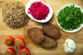 Meat cutlets, baked buckwheat on a wooden board . Red cabbage sauerkraut . Garlic, Onion, Tomatoes. Chopped coriander. Homemade