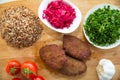 Meat cutlets, baked buckwheat on a wooden board . Red cabbage sauerkraut . Garlic, Onion, Tomatoes. Chopped coriander. Homemade