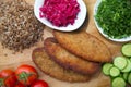 Meat cutlets, baked buckwheat on a wooden board . Red cabbage sauerkraut . Garlic, Onion, Tomatoes. Chopped coriander. Homemade