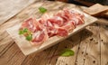 meat delicacy close-up with green leaves on a wooden background. dry-cured pork on a tray. meat with a layer of fat