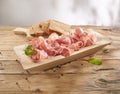 meat delicacy with green leaves and bread on a wooden background. dry-cured pork on a tray. meat with a layer of fat