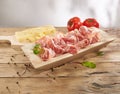 meat delicacy with green leaves cheese and tomatoes on a wooden background. dry-cured pork on a tray.