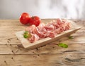 meat delicacy with green leaves and tomatoes on a wooden background. dry-cured pork on a tray. meat with a layer of fat