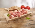 meat delicacy with tomatoes and bread on a wooden background. dry-cured pork on a tray. meat with a layer of fat