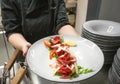 Meat dish in hand of chef, plate of tasty Carpaccio for hungry visitors of a restaurant