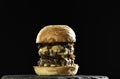 Meat double cheeseburger with caramelised onion on black plate