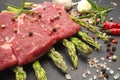 Meat food : raw beef fillet on black stone board with asparagus with dry spices ready to cooking