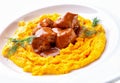 Meat goulash and mashed boiled yellow peas close-up on white plate