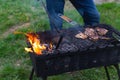 Meat is grilled. A man stirring coals with a hot poker. Sparks fly from fire in grill. Outdoor cooking. Picnic, weekend Royalty Free Stock Photo