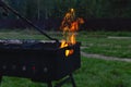 Meat is grilled. A man stirring coals with a hot poker. Sparks fly from fire in grill. Outdoor cooking. Picnic, weekend Royalty Free Stock Photo