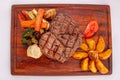 Meat grilled ribai with vegetables. Ribai steak on wooden board. Close up