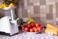 Meat grinder with pepper on the table next to tomatoes and carrots on the table in the kitchen, cooking homemade adijika, homemade Royalty Free Stock Photo