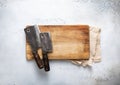 Meat hatchets on scratched cutting board and kitchen towel on light background. Top view