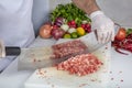 Chef is chopping the raw beef on cutting board with knife to cook in the kitchen, minced beef. Kebab restaurant, kebab preparation