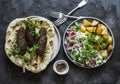 Meat kebab skewers, garlic tortillas naan, yogurt dressing vegetable salad, roasted potatoes - delicious lunch, tapas in the