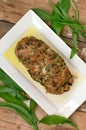 Meat loaf with fresh green buckrams leaves on white plate on wooden background Royalty Free Stock Photo